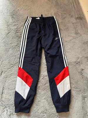 Adidas träningsbyxor blå/röd/vit - Dom är i bra skick har låssnat lite i Addids texsten men dom är inte använda mycke max 6 gånger 