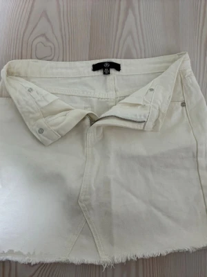 Vit jeanskjol - Supersöt vit jeanskjol med dragkedja. Den har fransning där nere o fickor där bak. Knappt använd!!🥰🥰