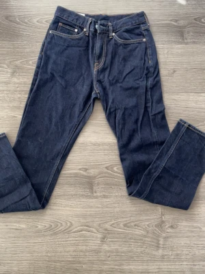 Mörkblå raka jeans  - Säljer ett par mörkblå jeans i klassisk rak modell med kontrastsömmar. Jeansen har fem fickor, bälteshällor och stängs med knapp och dragkedja. Perfekta för en clean och tidlös look.