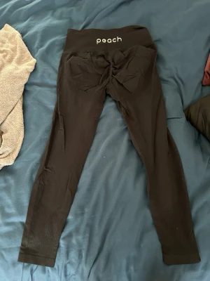 Svarta seamless leggings från Peach - Säljer ett par svarta seamless leggings från Peach med hög midja och ribbade detaljer vid bensluten. Stretchigt material som formar sig efter kroppen och scrunch-detalj bak. Perfekta för träning eller till vardags. Använda men i fint skick. Storlek S. 