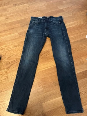 Mörkblå slim fit replay Jeans - Snygga mörkblå slim fit jeans . Jeansen har normal midja och raka ben, perfekta till en avslappnad stil. 31 32 storlek och ett pytte litet hål i skrevet