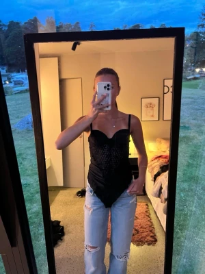 Svart spetsbody  - Säljer en svart body med tunna axelband och vadderade kupor. Bodyn har fina spetsdetaljer framtill och längs kanterna, vilket ger en elegant och trendig look. Perfekt att styla med jeans eller kjol för en snygg outfit. Säljer då den är för stor. Vet tyvärr inte vart den kommer ifrån, köpte den här på plick. Skriv för frågor🩷🫶🏼