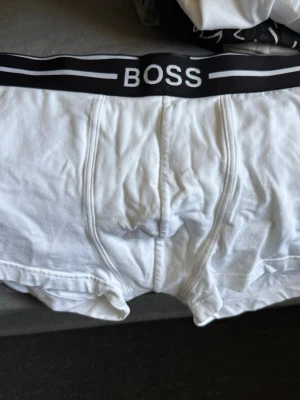 Svarta/vita  kalsonger från Hugo Boss - Snygga svarta/ vita kalsonger från Hugo Boss med bred resår i midjan och vita detaljer. Klassisk boxermodell med logga på linningen. Tillverkade i mjukt och stretchigt material för skön passform. De är aldrig använda och de finns 3 pack, 2 svarta och ett par vita. 3 pack 
