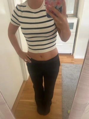 Vit croppad randig topp - Säljer en vit croppad topp med mörkblå horisontella ränder. Toppen har rund halsringning och korta ärmar. Perfekt för en chill och trendig look. Storlek L men väldigt liten i storleken sitter som xs/s