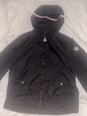 Moncler windbreaker  - Säljer en svart Moncler windbreaker i svart. Jackan har en klassisk passform och är tillverkad i ett glansigt material som ger en exklusiv känsla. Perfekt för kalla eller vindiga dagar och riktigt snygg till streetwear-stilen.