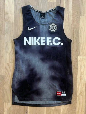 Nike F.C. Dri-FIT träningslinne – Storlek S – Mycket fint skick - Säljer ett stilrent Nike F.C. Dri-FIT träningslinne i storlek S. Svart med grå detaljer och den klassiska NIKE F.C.-loggan framtill. Lätt och ventilerande material som passar perfekt för träning, fotboll eller vardagsbruk.  * Märke: Nike F.C. * Storlek: S * Skick: Mycket fint skick * Material: Dri-FIT – ventilerande och fukttransporterande * Färg: Svart/grå  En utgången Nike F.C.-modell som är svår att hitta i detta skick.  Pris: 399 kr.
