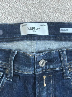 Replay Hyperflex blå jeans - Säljer ett par mörkblå Replay Hyperflex jeans i modellen Grover. Klassisk femficksdesign med stretchigt material för extra komfort. Snygga kontrastsömmar och detaljer som ger en modern look. Perfekta för dig som vill ha både stil och rörelsefrihet. Jeansen är i storlek 31 (W) och 30 (L). Tveka inte att höra av dig vid frågor! 
