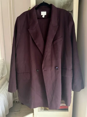 Mörklila oversized kavaj och byxor  - Säljer en snygg mörklila kavaj med dubbelknäppning och klassisk krage samt byxor. Kavajen har två framfickor och en bröstficka, samt en oversized passform som ger en avslappnad look. .