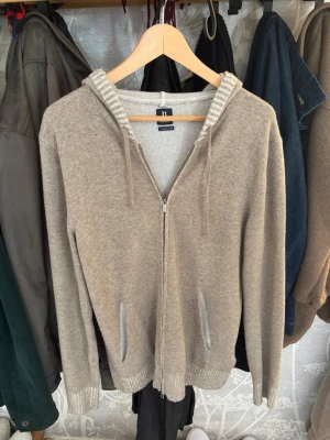Beige zip-hoodie från Boggi Milano - Mysig beige hoodie med dragkedja och huva.  Insidan av huvan har en ljusare ribbad kant som ger en snygg kontrast. Perfekt för chill dagar eller när du vill ha något bekvämt och stilrent. 