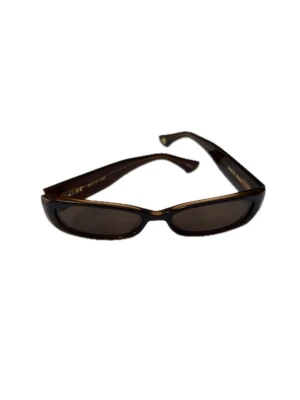 Bruna smala solglasögon från Corlin - Snygga smala solglasögon från Corlin Eyewear i mörkbrunt med rektangulära glas och breda skalmar. Glasögonen är modellen Romy och färgen Brown Brown, de har en diskret logga i silver på sidan. Kostar 1299 kr nya. Saknar originala fodralet men är i gott skick och utan repor på glaset. 100% UVA och UVB skydd.
