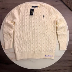 Polo Ralph Lauren kabelstickad tröja vit/cream - Klassisk kabelstickad tröja från Polo Ralph Lauren i vit/cream färg.                                                                                  Mjuk och bekväm kvalitet med rund halsen. Passar mycket för sommaren                                                                         Storlek L                                                               Skick skick 10/10  