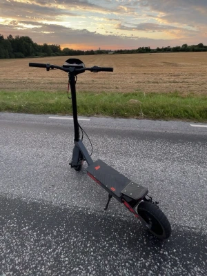 Svart el-scooter Kukirin G2 - Säljer en svart el-scooter Kukirin G2 med orange detaljer. Scootern har bred fotplatta med mönster, stora hjul och robust ram. Perfekt för att ta sig fram snabbt i stan. Laddare medföljer och den har tydlig display på styret.