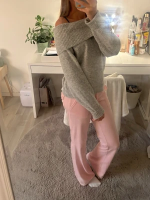 Grå off shoulder stickad tröja - Säljer en supermjuk grå stickad tröja med bred off shoulder-krage och långa ärmar. Tröjan har ribbade muddar vid ärmslut och nederkant, perfekt för dig som gillar en avslappnad men ändå trendig stil.