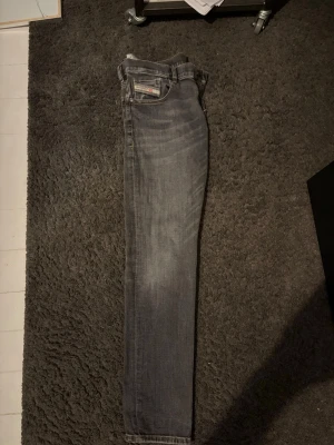 Grå slim fit jeans från Diesel  - Säljer ett par grå slim fit jeans med snygga slitningar och tvättade detaljer. Jeansen har klassisk femficksmodell och normal midja. Perfekta för dig som gillar en smalare passform och vill ha ett par stilrena jeans till din garderob.