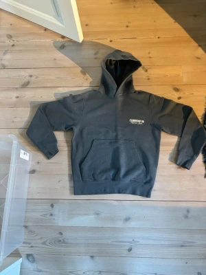 Mörkgrå hoodie från Jack & Jones - Snygg mörkgrå hoodie från Jack & Jones med tryck på bröstet. Klassisk känguruficka framtill och huva. Tillverkad i mjukt bomullsmaterial som är skönt att ha på sig. Perfekt för en avslappnad och trendig stil.