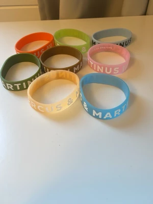 Färgglada silikonarmband Marcus & Martinus - Säljer ett set med åtta silikonarmband i olika färger med texten Marcus & Martinus. Armbanden är i färgerna orange, grön, ljusblå, rosa, gul, brun, olivgrön och blå. Perfekta för dig som gillar färgglada accessoarer och vill visa ditt stöd för Marcus & Martinus.