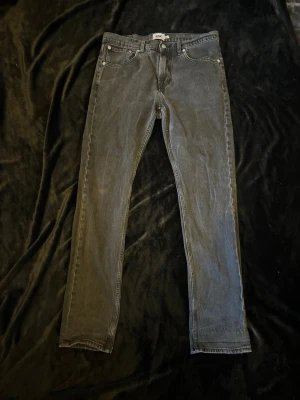 Svarta raka jeans från 157 - Snygga svarta jeans från 157 med rak passform och klassisk femficksdesign. Jeansen har normal midja och silverfärgade detaljer vid knappar och nitar. Materialet är denim i bomull som ger en tidlös look. Storlek: W32 L34
