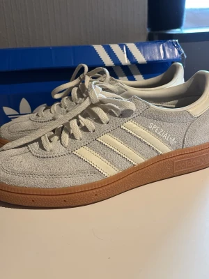 Adidas Spezial nya - Snygga Adidas Spezial sneakers i ljusgrå/mint mocka med klassiska vita ränder på sidorna och gummisula i brunt. Skorna har lågt skaft och vita skosnören. Perfekta för dig som gillar basic men endån lite utstickande. Använda en gång men box o allt finns kvar. De är mer grå blå ljus blå men de ser lite gråa ut men de är jätte fina men de passa inte tyvärr💕 öppen för prisförslag men inte skambud