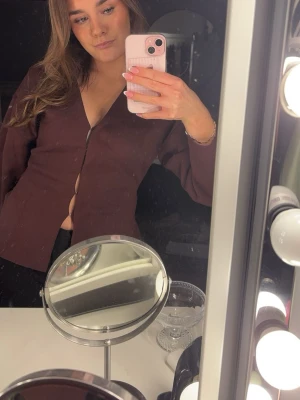 Mörkbrun skjorta med dragkedja - Säljer en mörkbrun blus med lång ärm och hakar framtill. Blusen har en clean look och är lätt att styla till olika outfits. Passformen är jättefin😍.