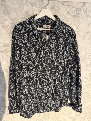Svart blommig skjorta Dressmann - Tjena, säljer nu en snygg svart skjorta med vitt blommigt mönster från dressmann i storlek M. Den är aldrig använd bara testad, har du någon fundering är de bara att skriva, ge gärna prisförslag!!