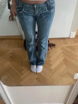 Blå bootcut jeans med slitningar - Säljer ett par blå bootcut jeans med snygga slitningar. Gör outfiten lite roligare