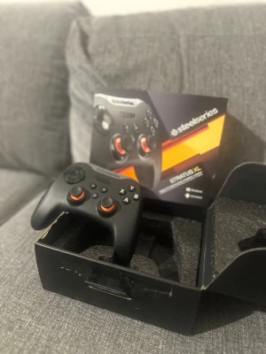 SteelSeries Stratus XL handkontroll - SteelSeries Stratus XL är en svart trådlös handkontroll med orange detaljer runt styrspakarna. Den har klassisk form med två analoga spakar, styrkors, fyra knappar (A, B, X, Y) och triggers. Perfekt för gaming på PC eller Android.