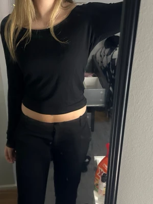 Svart croppad långärmad topp - Säljer en svart croppad långärmad topp med rund halsringning. Enkel och stilren design som passar till det mesta. Tillverkad i mjukt material som känns skönt mot huden.
