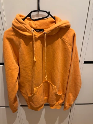 Orange hoodie från BikBok XS - Säljer en snygg orange hoodie från BikBok i storlek XS. Hoodien har en stor huva med dragsko, magficka och ribbade muddar vid ärmar och nederkant. Tillverkad i mjukt och skönt material, perfekt för chill dagar.