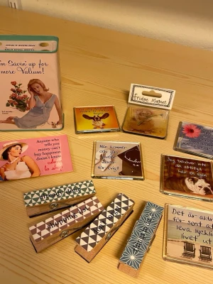 Samling kylskåpsmagneter och klämmor - Säljer en mix av kylskåpsmagneter och stora klämmor med olika citat och motiv. Magneterna har färgglada bilder, texter och retroinspirerade illustrationer. Klämmorna är dekorerade med mönster och ord som 'shopping' och 'happiness'. Perfekt för att piffa upp kylskåpet eller anslagstavlan.