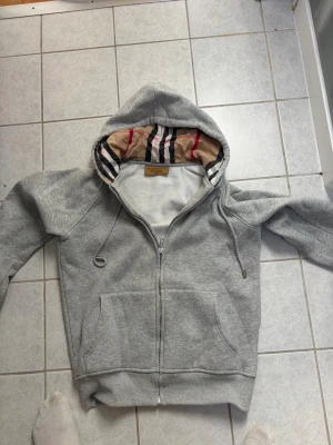 Grå burberry hoddie  - Säljer en burberry hoodie för att jag har tröttnat på den. Storleken är M men den känns mer som S så skulle nog säga att den passar 165-172 beroende på hur man vill att den ska sitta. Priset kan diskuteras!