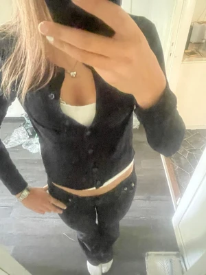 Svart  kofta med knappar - En svart, figurnära kofta med rund halsringning och knäppning framtill. Koftan har långa ärmar och är tillverkad i ett mjukt, stretchigt material som passar perfekt till lager på lager. Enkel och stilren design som funkar till det mesta.