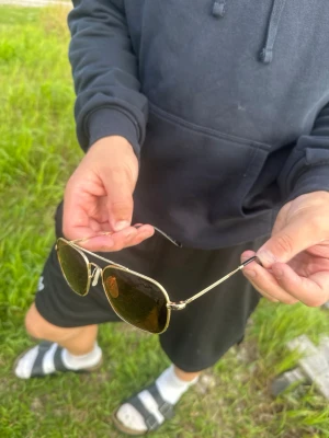 Ray-Ban aviator solglasögon guld - Snygga aviator solglasögon från Ray-Ban med tunna guldfärgade metallbågar och mörka linser. Klassisk och tidlös design som passar till alla outfits. Perfekta för soliga dagar. Pris kan diskuteras 😀