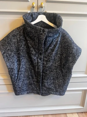 Completely new stylish short-sleeve high-neck jacket in a beautiful black & grey textured fabric 🖤 - A unique statement jacket with a chic, structured silhouette and an oversized high collar. The short sleeves give it a modern, sophisticated look, while the textured monochrome fabric makes it super easy to style.   Original price 2000 kr