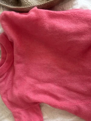 Rosa stickad tröja mohair h&m - Mysig rosa stickad tröja med rund halsringning och långa ärmar. Tröjan har ribbade muddar vid halsen och är tillverkad i ett mjukt material som känns skönt mot huden. Perfekt för kyligare dagar och enkel att matcha med jeans eller kjol.