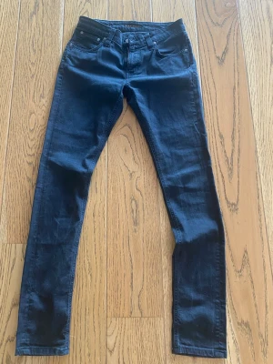 Nudie Jeans - Mörkblå Nudie Jeans i slim fit med klassisk femficksdesign och raka ben. Premium denim med mjukt, följsamt tyg –väldigt bekväma hela dagen. Nytt skick, inga fläckar eller slitage. Passar både streetstyle och clean look. Skickas snabbt och välpackat. W29 L32