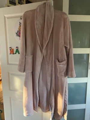 Soft Pink Bathrobe - This is a soft, light pink bathrobe made from recycled polyester. It features two front pockets and a tie belt. 