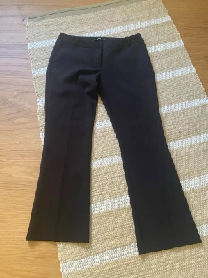 Svarta kostymbyxor från BikBok - Snygga svarta kostymbyxor från BikBok i storlek 40. Byxorna har en klassisk rak passform med lätt utsvängda ben och pressveck framtill. Perfekta till en stilren look och passar till många olika outfits. Dem är i modellen VERA och är SHORT! 💞