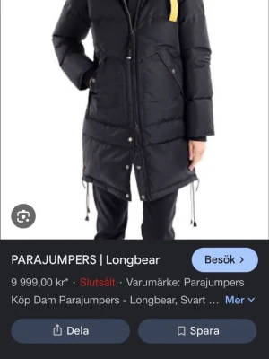 Svart lång dunjacka från Parajumpers - Snygg svart lång dunjacka från Parajumpers med dragkedja och knappar framtill. Jackan har en gul detalj vid halsen, justerbar nederkant och stora fickor. Perfekt för kalla vinterdagar och har en modern, stilren look.