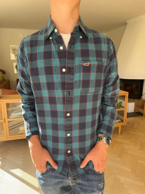 Hollister skjorta rutig overshirt vintage herr - Rutig långärmad skjorta från Hollister i en snygg mörkgrön och blå färgkombination med röda detaljer. Hollister-loggan broderad i rött på bröstfickan. Väldigt mångsidig och passar lika bra till vardags som till helgen. Fint skick utan anmärkningar.#hollistershirt #grönskjorta #rutig #flannelshirt #skjorta #casualwear #y2k #mensfashion #trend #retro