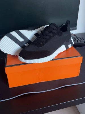 H Skor/Sneakers - Stilrena svarta sneakers med chunky vit sula och svarta skosnören. Ovandelen är i textil och mockaliknande material, med detaljer i svart och vit. Perfekta för en trendig och sportig look.                                           Nya Oanvända 🔥.                                              