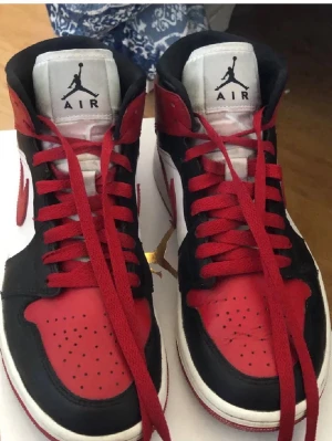 Air Jordan 1 mid - Säljer ett par Air Jordan 1 sneakers i röd, svart och vitt.  strl 37,5.