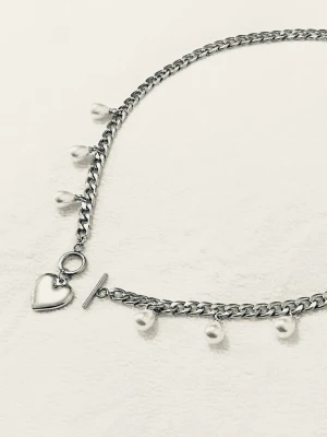 Silverfärgat halsband med pärlor och hjärta - Snyggt halsband i silverfärgad rostfritt med små vita pärlor som hänger längs kedjan och ett hjärtformat hänge framtill. Halsbandet har en chunky kedja och ett dekorativt T-lås som detalj. Perfekt accessoar för att lyfta din outfit.