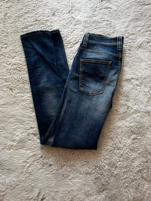 Nudie jeans - Snygga blå skinny jeans från Pull&Bear med slitningar och tvättade detaljer. Klassisk femficksmodell med normal midja och smala ben. Jeansen har kontrastsömmar och patch bak i midjan. Perfekta för en avslappnad och trendig look. Priset kan diskuteras vid snabb affär😎i storlek 29:34