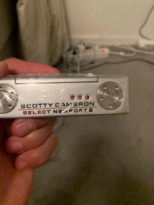 Scotty Cameron Select Newport 2 putter - Säljer en Scotty Cameron Select Newport 2 putter i silverfärgat metall med röda detaljer och rött grepp. Perfekt för golfare som vill ha en stilren och klassisk putter med bra känsla. Ligger skönt i handen och har snygg design. Storlek 33