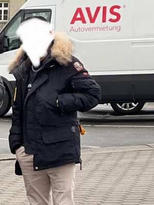 Mörkblå Parajumpers - Snygg mörkblå Parajumpers med stor pälskantad huva och flera praktiska fickor. Jackan har detaljer i gult och patch på ärmen. Perfekt för kalla dagar och ger en cool streetlook.