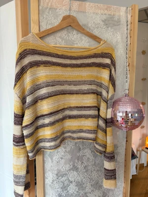 Randig stickad tröja i gult och brunt - Trendig stickad tröja med breda horisontella ränder i gult, brunt och beige. Tröjan har en lös passform, långa ärmar och en något vid halsringning. Perfekt för dig som gillar en avslappnad och färgglad stil.