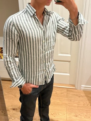 Randig linneskjorta från These Glory Days - Säljer en snygg randig skjorta från These Glory Days i vitt och mörkgrönt. Modellen är slimfit. Storlek S. Tillverkad i ett luftigt och skönt linne. Inga defekter. Hör av dig vid frågor🤙