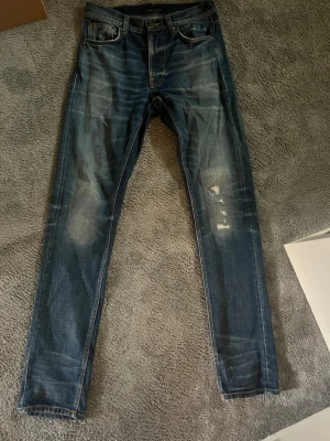 Nudie jeans  - Hej, jag säljer ett par super snygga nudie jeans, de är slim fit. Byxorna är i perfekt skick och slitningarna är orginal. De här jeansen säljs inte i vanliga nudie buktiker då de var en begränsad upplaga! De är storlek  W30 L32. De här är ett par jeans som sticker ut men inte för mycket, du kommer aldrig se någon annan med exakt samma.