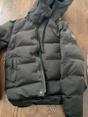  Svart dunjacka med huva - Svart vinterjacka snygg och skön, den har bara ett litet hål men syns inte när man har på sig den