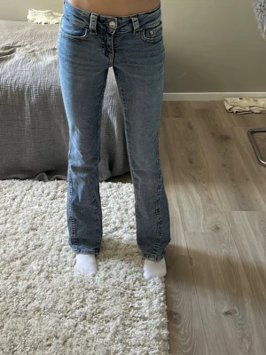 Blå bootcut jeans med fickdetaljer - Säljer ett par ljusblå bootcut jeans med snygga sömmar och unika fickdetaljer bak. Jeansen är låg midjade/normal midja 